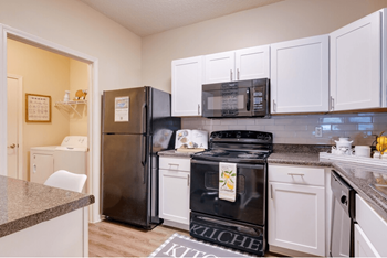 A kitchen with white cabinets and black appliances